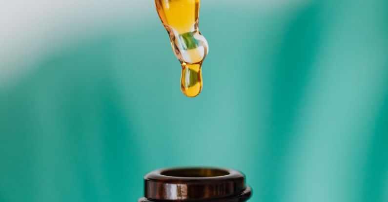 Remedies - Closeup of anonymous doctor with pipette for fluid dripping yellow medication in brown glass vial while making procedure in clinic